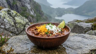 Campfire chilli in a cast iron Dutch oven over glowing hardwood coals, steam rising into the night air